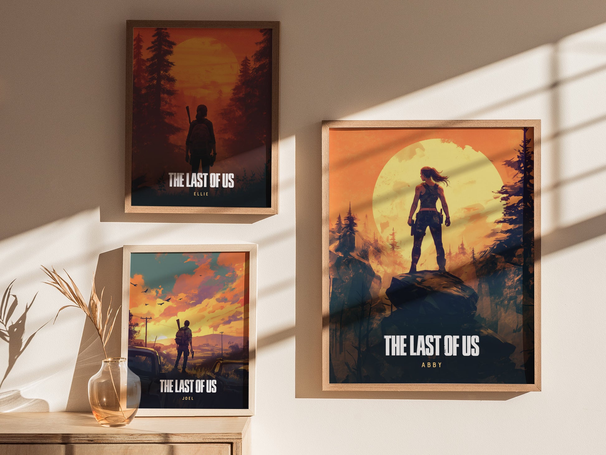 Three framed posters of The Last of Us characters—Ellie, Abby, and Joel—are displayed on a sunlit wall, each set against dramatic forested landscapes.