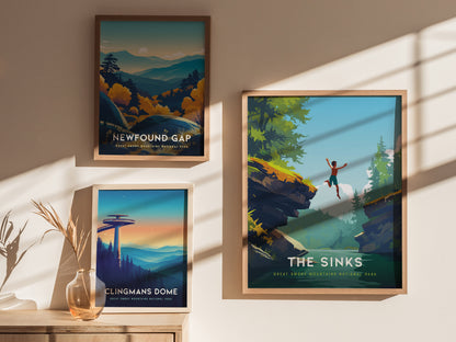 Three framed posters hang on a sunlit wall. The top left features Newfound Gap with a mountainous landscape, the bottom left shows Clingmans Dome at sunset, and the right displays The Sinks with a person leaping over a waterfall.