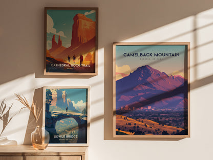 Three framed posters are displayed on a sunlit wall, featuring Camelback Mountain, Cathedral Rock Trail, and Devils Bridge with vibrant desert landscapes and hiking scenes.