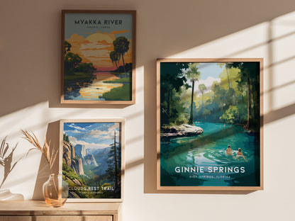 Three framed posters on a wall: Myakka River with a sunset scene, Clouds Rest Trail featuring a mountainous landscape, and Ginnie Springs showing two people wading in turquoise waters.