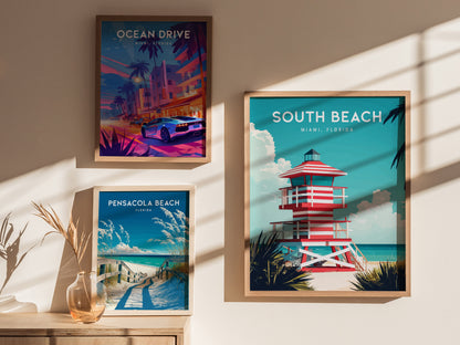 Three framed posters are displayed on a wall, featuring vibrant scenes: a colorful Ocean Drive with a car, a serene Pensacola Beach pathway, and a striking South Beach lifeguard tower against a bright sky.