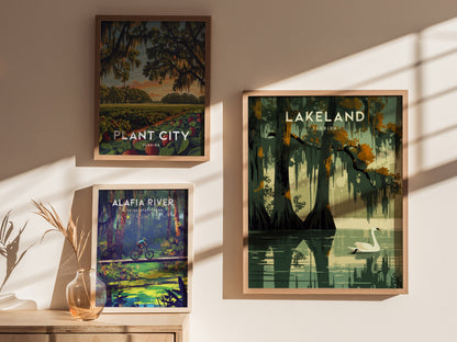 Three framed posters on a sunlit wall depict Plant City, Lakeland, and Alafia River with vibrant natural scenes, including a swan on a lake and a cyclist in a forest.