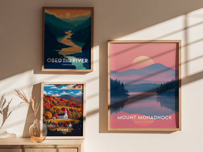 Three framed posters on a beige wall depict scenic landscapes: Obed Wild & Scenic River, Tennessee; Stowe, Vermont with autumn foliage; and Mount Monadnock, New Hampshire at sunset.