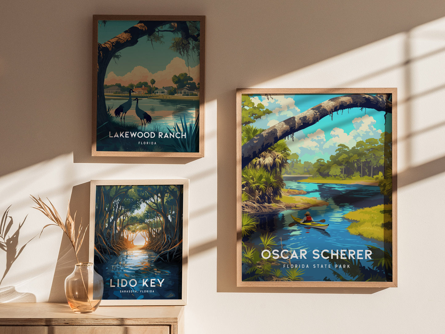 Three framed art prints are displayed on a wall, featuring Florida landscapes: Lakewood Ranch with cranes, Lido Key with mangroves, and Oscar Scherer State Park with a kayaker.