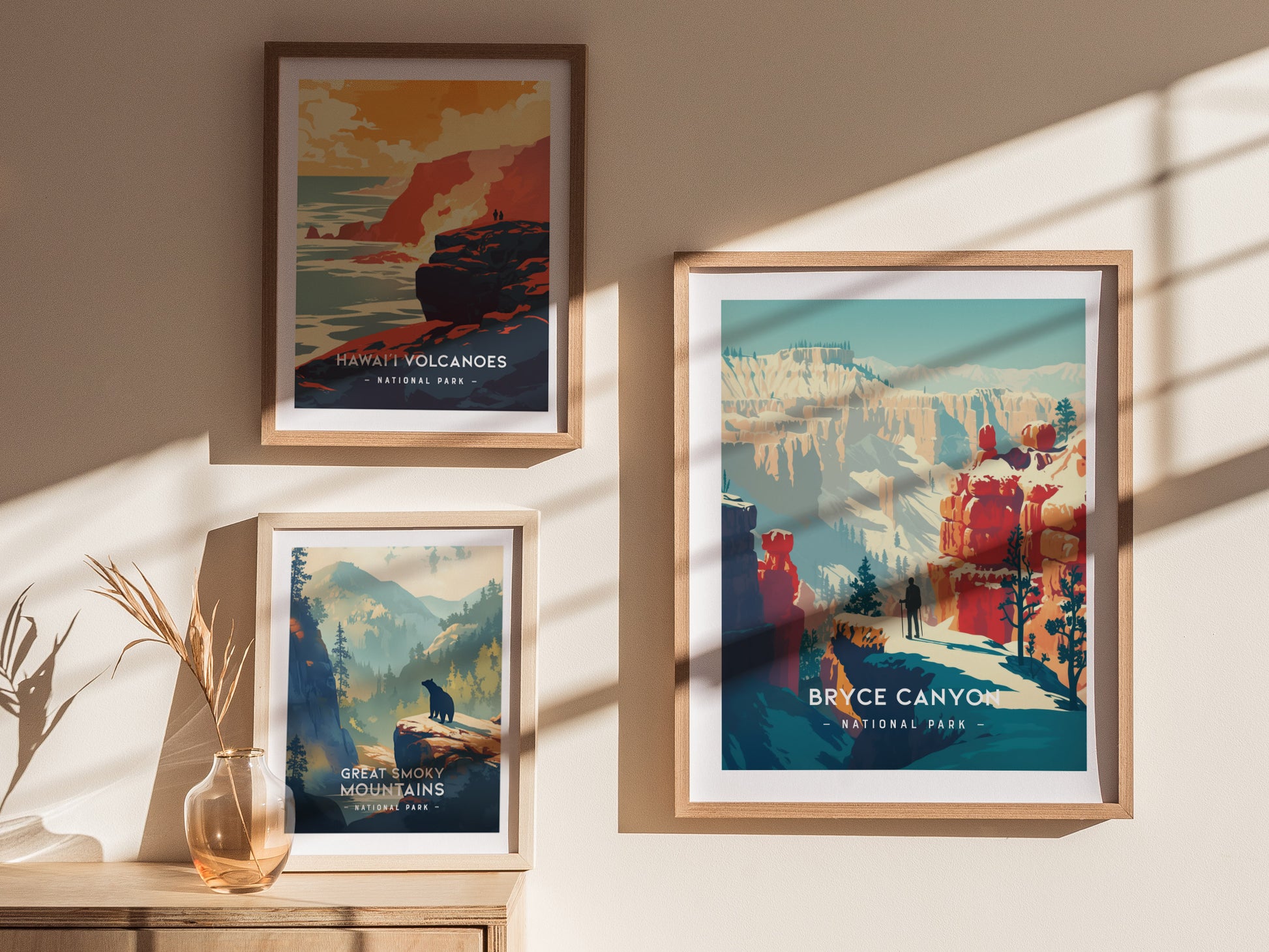 Three framed minimalist national park prints hang on a wall, featuring Bryce Canyon, Hawaii Volcanoes, and Great Smoky Mountains, illuminated by soft sunlight.