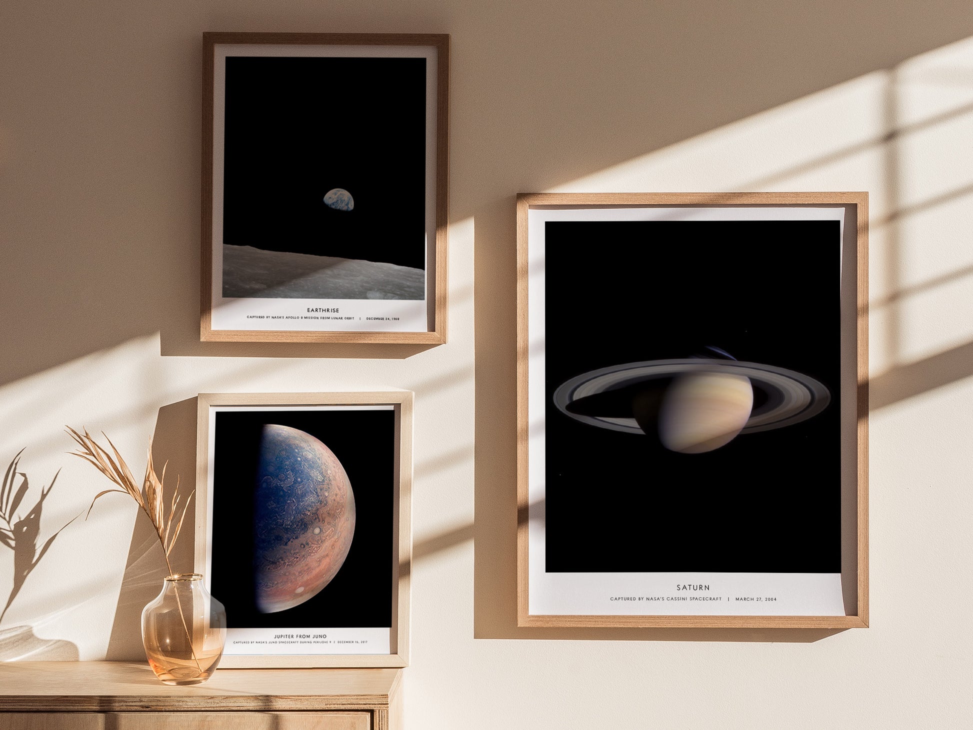 Framed space-themed prints of celestial bodies on a wall with sunlight casting shadows.
