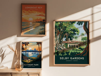 Three framed posters hang on a wall, featuring vibrant landscapes of Longboat Key, Bayfront Park, and Selby Gardens in Sarasota, Florida, all illuminated by soft sunlight.