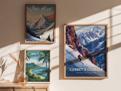 Three framed posters are displayed on a wall, featuring Lone Peak, Waikiki, and Corbets Couloir, with sunlight casting shadows across them. A vase with dried branches sits below.