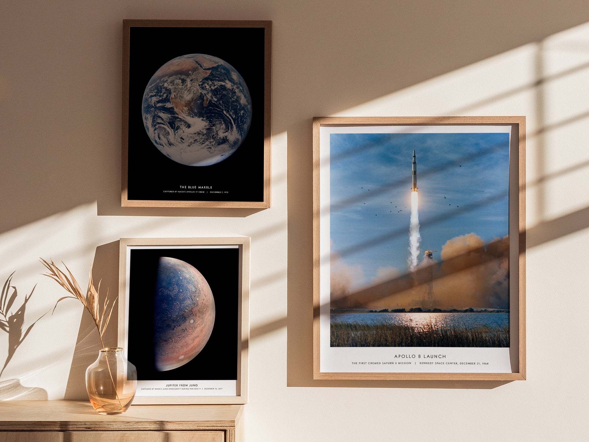 Framed space-themed prints on a wall with sunlight casting shadows.