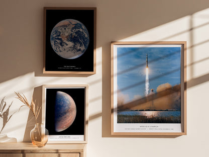 Framed space-themed prints on a wall with sunlight casting shadows.