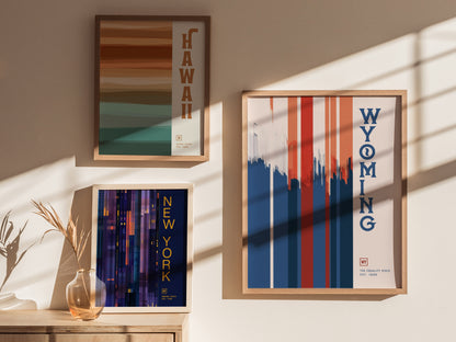 Three framed posters on a sunlit wall feature minimalist designs for Hawaii, Wyoming, and New York. Shadows from window panes add a dynamic touch to the scene.