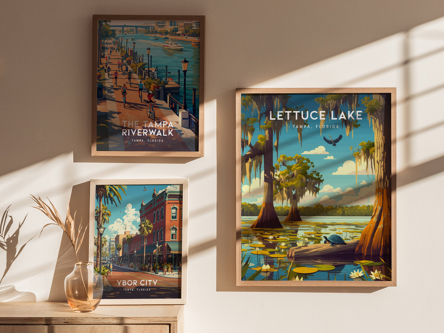 Framed art posters feature scenic illustrations of Tampa, Florida, including Lettuce Lake, Tampa Riverwalk, and Ybor City, displayed on a sunlit wall with a decorative vase.