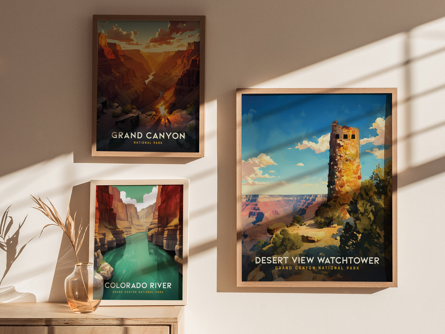Three framed posters on a wall depict scenic views of the Grand Canyon, Colorado River, and Desert View Watchtower, with sunlight casting shadows across them.