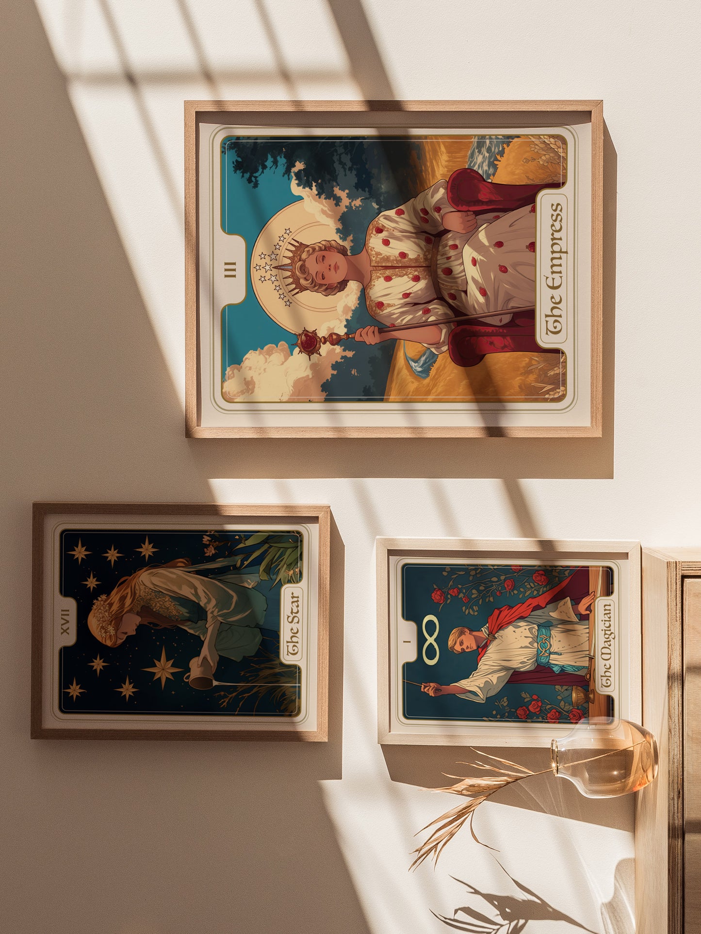 Three framed tarot card posters are displayed on a sunlit wall, featuring The Empress, The Star, and The Magician, with a vase of dried plants nearby.