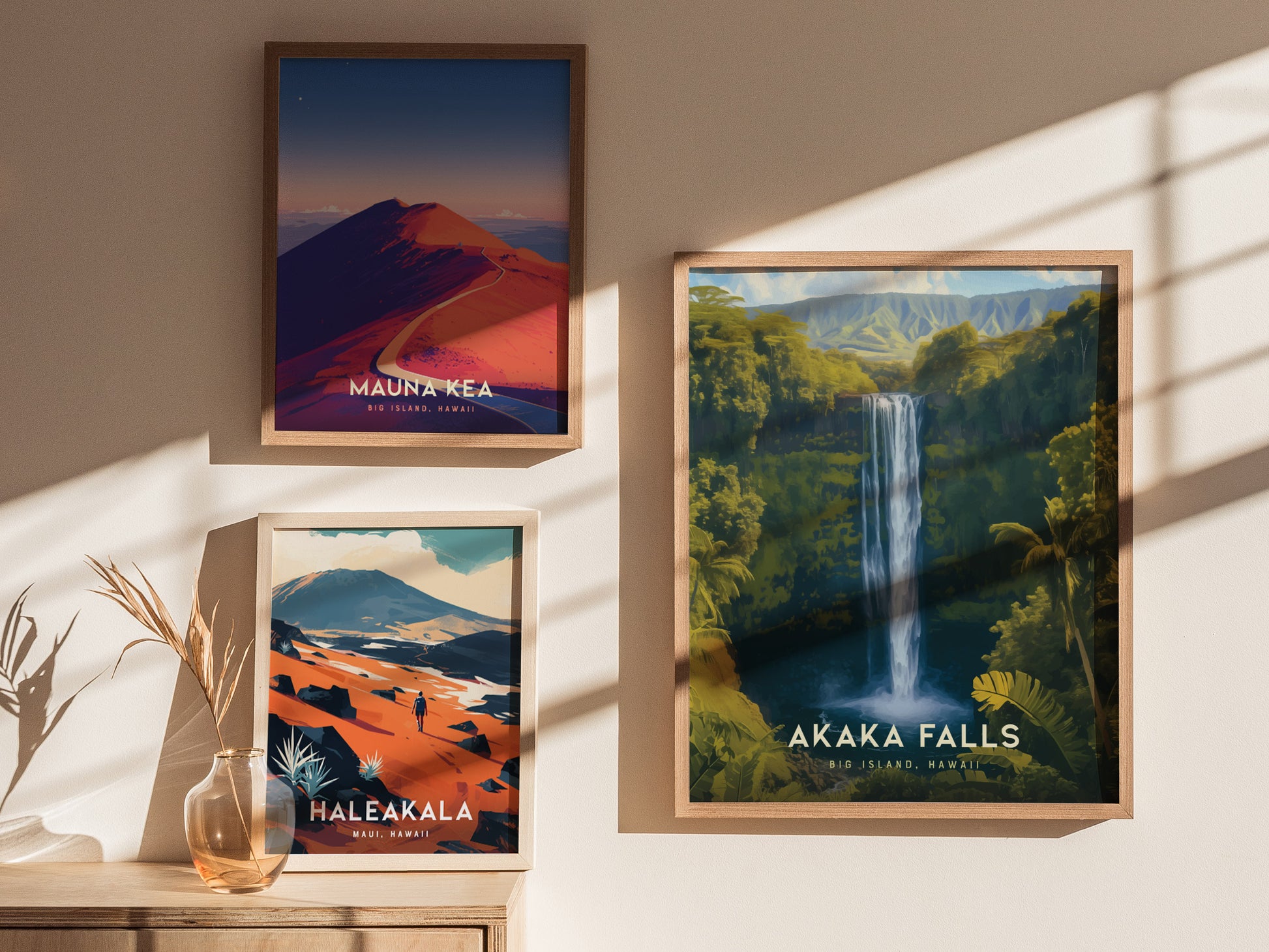 Three framed posters are displayed on a wall. They depict Mauna Kea, Haleakala, and Akaka Falls, showcasing vibrant landscapes with mountains, a waterfall, and lush greenery.