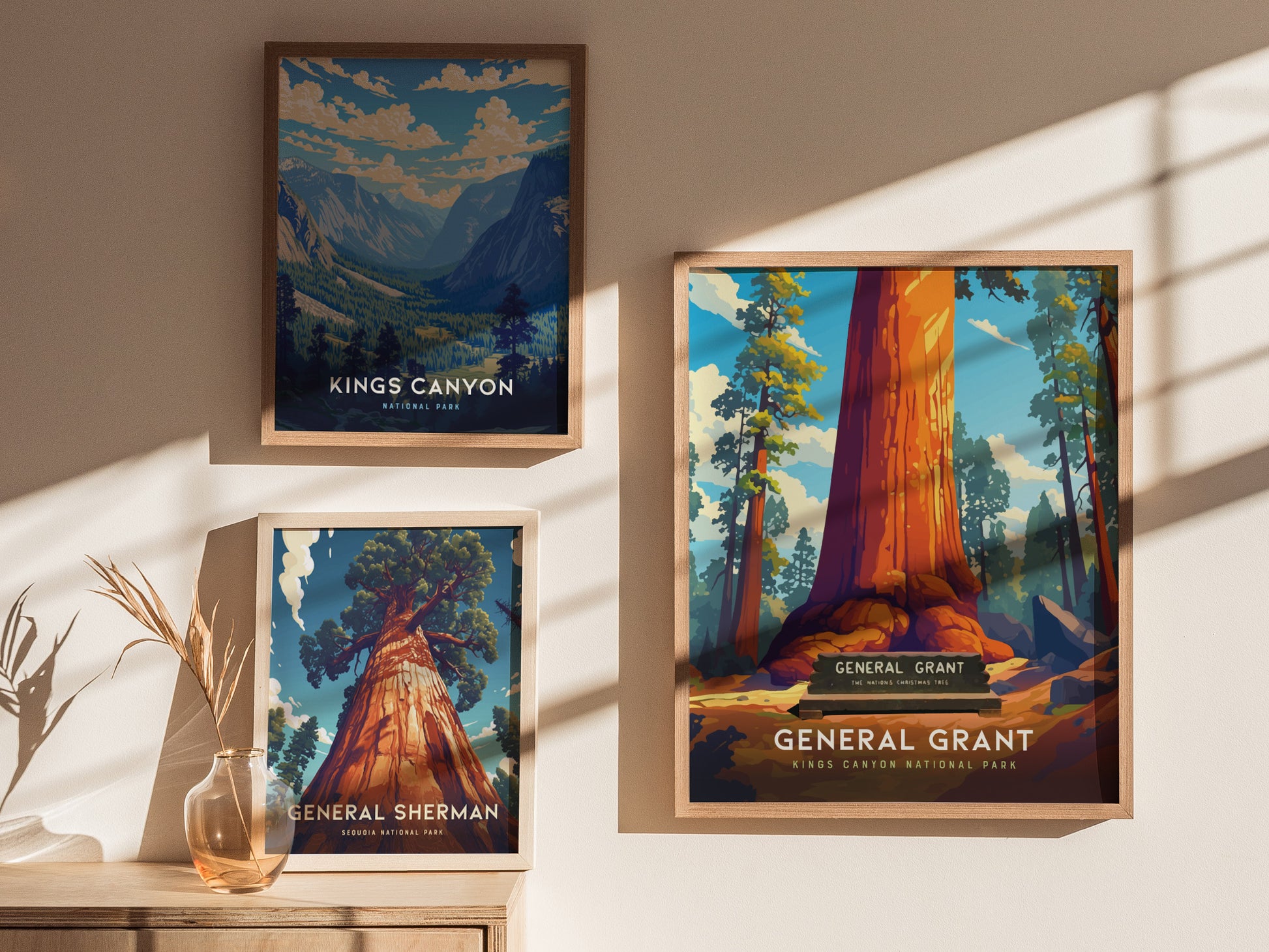 Three framed posters are displayed on a wall, featuring vibrant illustrations of Kings Canyon, General Grant, and General Sherman trees, with sunlight casting shadows across them.