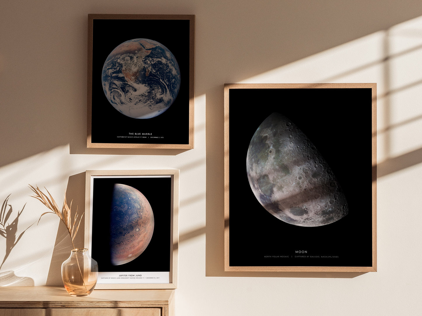 Framed prints of celestial bodies on a wall with sunlight casting shadows.