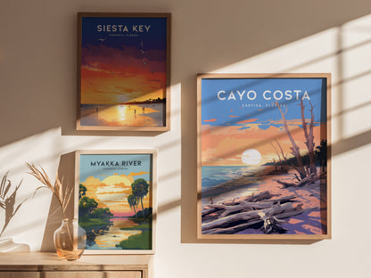 Three framed posters are displayed on a wall, depicting Siesta Key, Myakka River, and Cayo Costa, each featuring vibrant sunset scenes with landscapes and water.