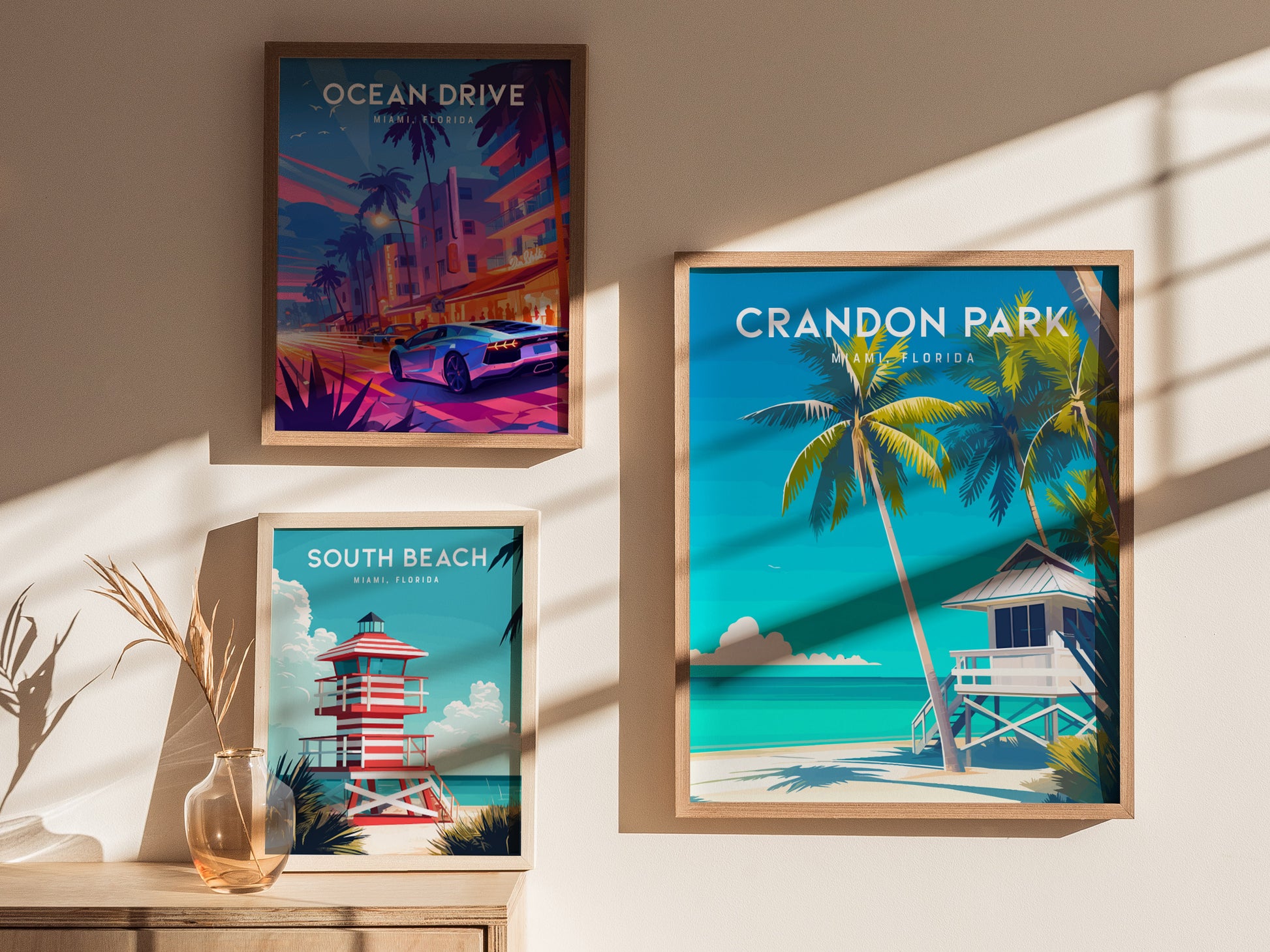 Three framed posters are displayed on a wall, each depicting Miami locations. The Crandon Park poster shows palm trees and a lifeguard tower by the beach.