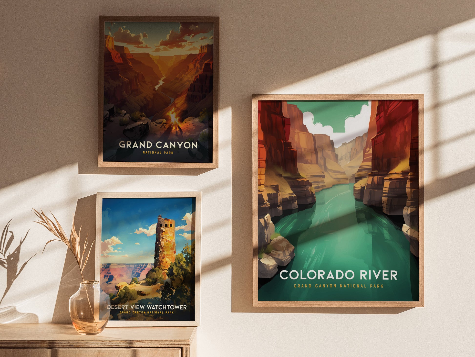 Three framed posters are displayed on a wall, depicting the Grand Canyon, the Colorado River, and the Desert View Watchtower, with sunlight casting shadows across them.