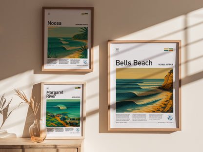Framed posters featuring Bells Beach, Noosa, and Margaret River hang on a beige wall, with sunlight casting shadows. A small vase with dried plants is placed nearby.