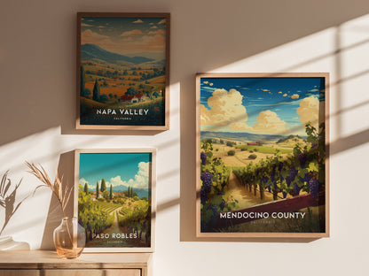 Framed posters of Napa Valley, Paso Robles, and Mendocino County are displayed on a sunlit wall, featuring vibrant vineyard and countryside landscapes. A vase with dried grass sits below.