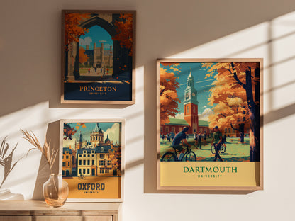 Framed posters of Princeton, Oxford, and Dartmouth University hang on a sunlit wall, with a vase of dried plants on a wooden table below.