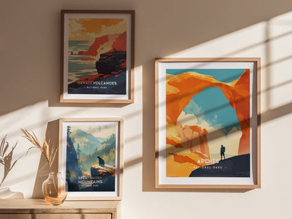 Three framed posters hang on a wall, depicting Hawaii Volcanoes, Arches, and Great Smoky Mountains National Parks, with shadows cast across the artwork and a vase nearby.