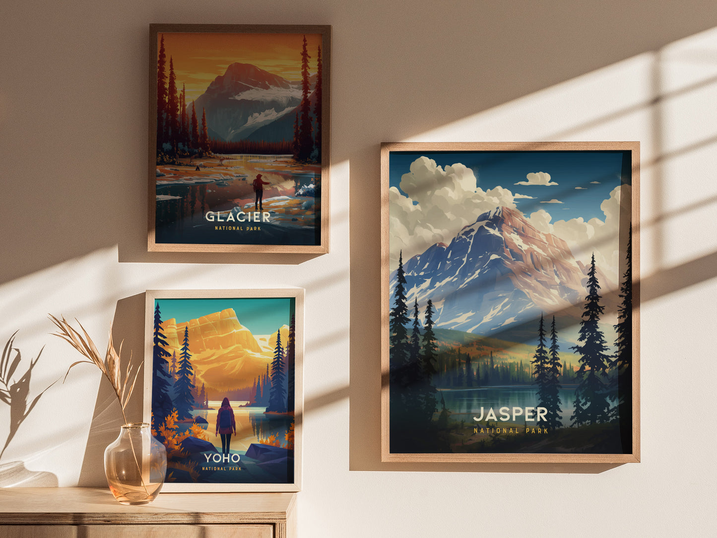 Three framed posters hang on a wall, depicting scenic landscapes of Glacier, Yoho, and Jasper National Parks. Sunlight casts shadows, enhancing the warm, inviting atmosphere.