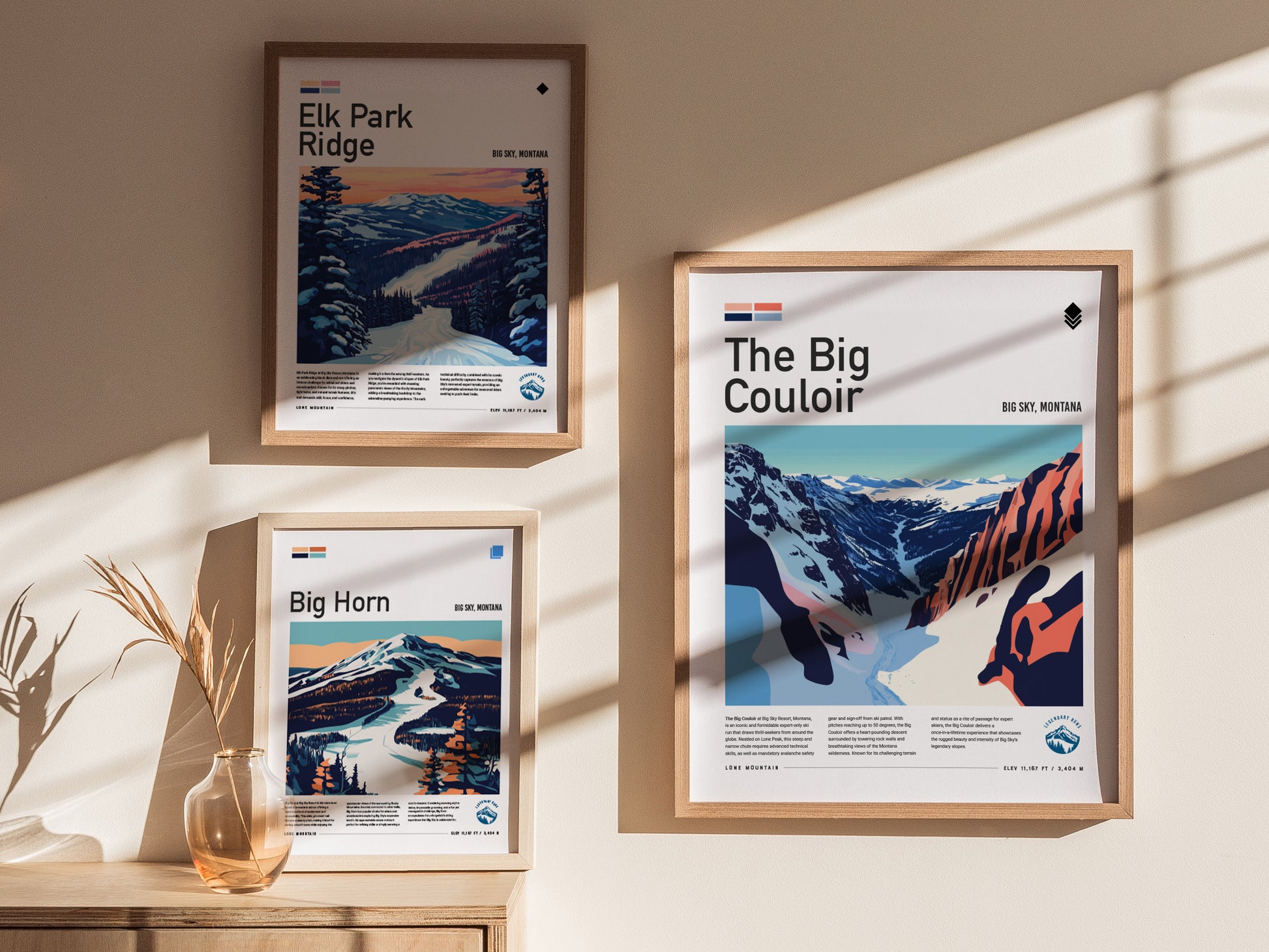 Three framed posters are displayed on a sunlit wall, featuring ski runs from Big Sky, Montana, including The Big Couloir, Elk Park Ridge, and Big Horn, with a decorative vase.