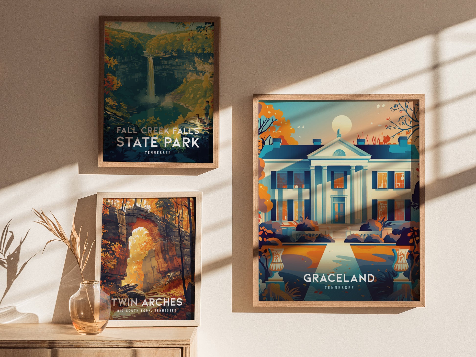 Three framed posters hang on a sunlit wall, depicting Fall Creek Falls State Park, Twin Arches, and Graceland in vibrant colors, each showcasing scenic or iconic landmarks.