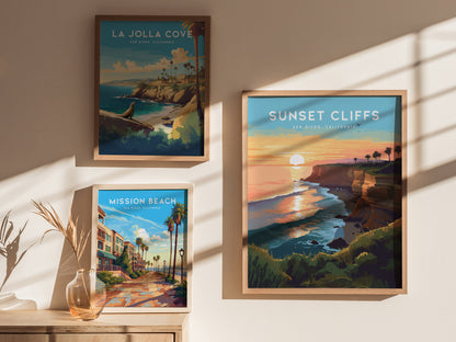Three framed posters are displayed on a sunlit wall, featuring scenic views of La Jolla Cove, Sunset Cliffs, and Mission Beach in San Diego, California.