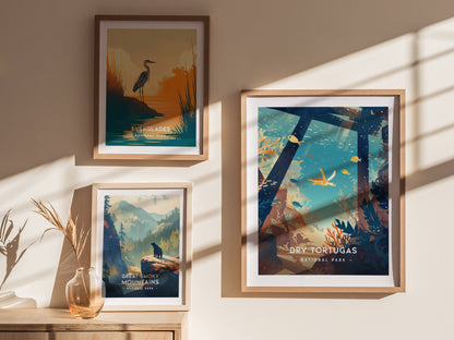 Three framed posters are displayed on a wall: Everglades with a heron, Great Smoky Mountains with a wolf, and Dry Tortugas with marine life. Sunlight creates shadows.