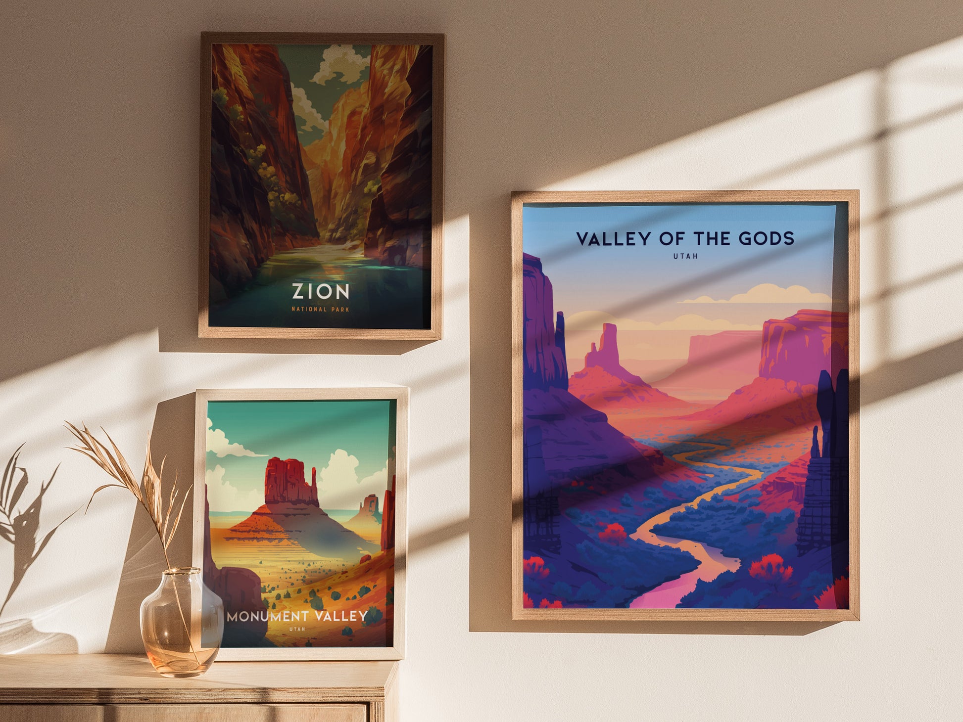 Three framed posters on a wall depict Zion National Park, Monument Valley, and Valley of the Gods. Sunlight casts shadows, enhancing the vibrant colors of the landscapes.