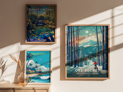 Three framed posters are displayed on a wall, showcasing Sunken Gardens, Tamarindo, and Ore Bucket in Breckenridge, Colorado. Soft sunlight casts shadows across the art.