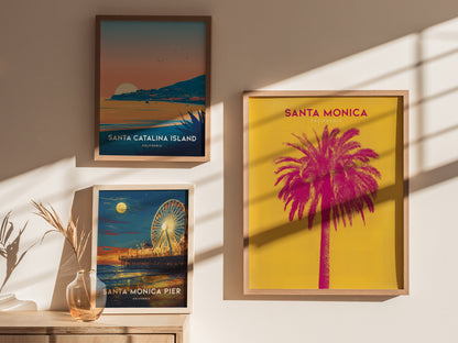 Three framed posters are displayed on a sunlit wall. They feature vibrant scenes of Santa Catalina Island, Santa Monica Pier, and a colorful palm tree against a bright yellow background.
