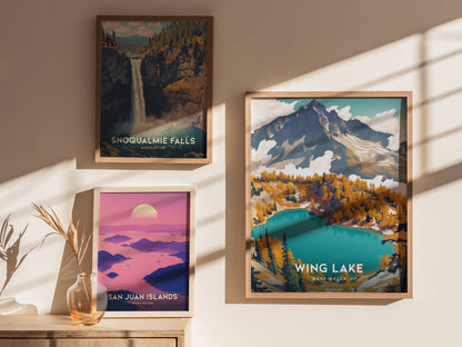 Framed posters of Snoqualmie Falls, San Juan Islands, and Wing Lake are displayed on a sunlit wall, with a decorative vase on a wooden surface nearby.