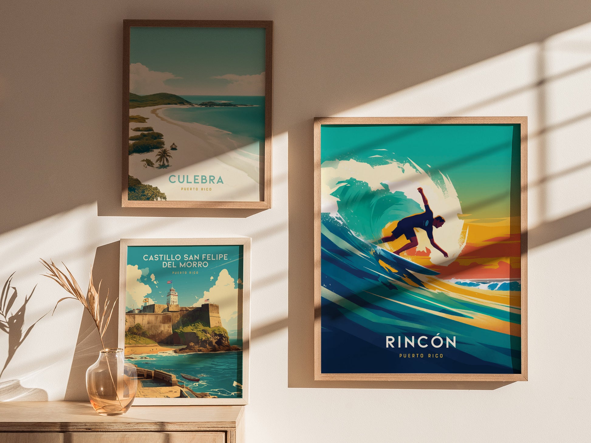Framed artwork on a wall includes a vibrant Rincon surfing poster, a scenic Culebra beach image, and a Castillo San Felipe del Morro print. Sunlight casts shadows across the display.