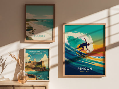 Framed artwork on a wall includes a vibrant Rincon surfing poster, a scenic Culebra beach image, and a Castillo San Felipe del Morro print. Sunlight casts shadows across the display.