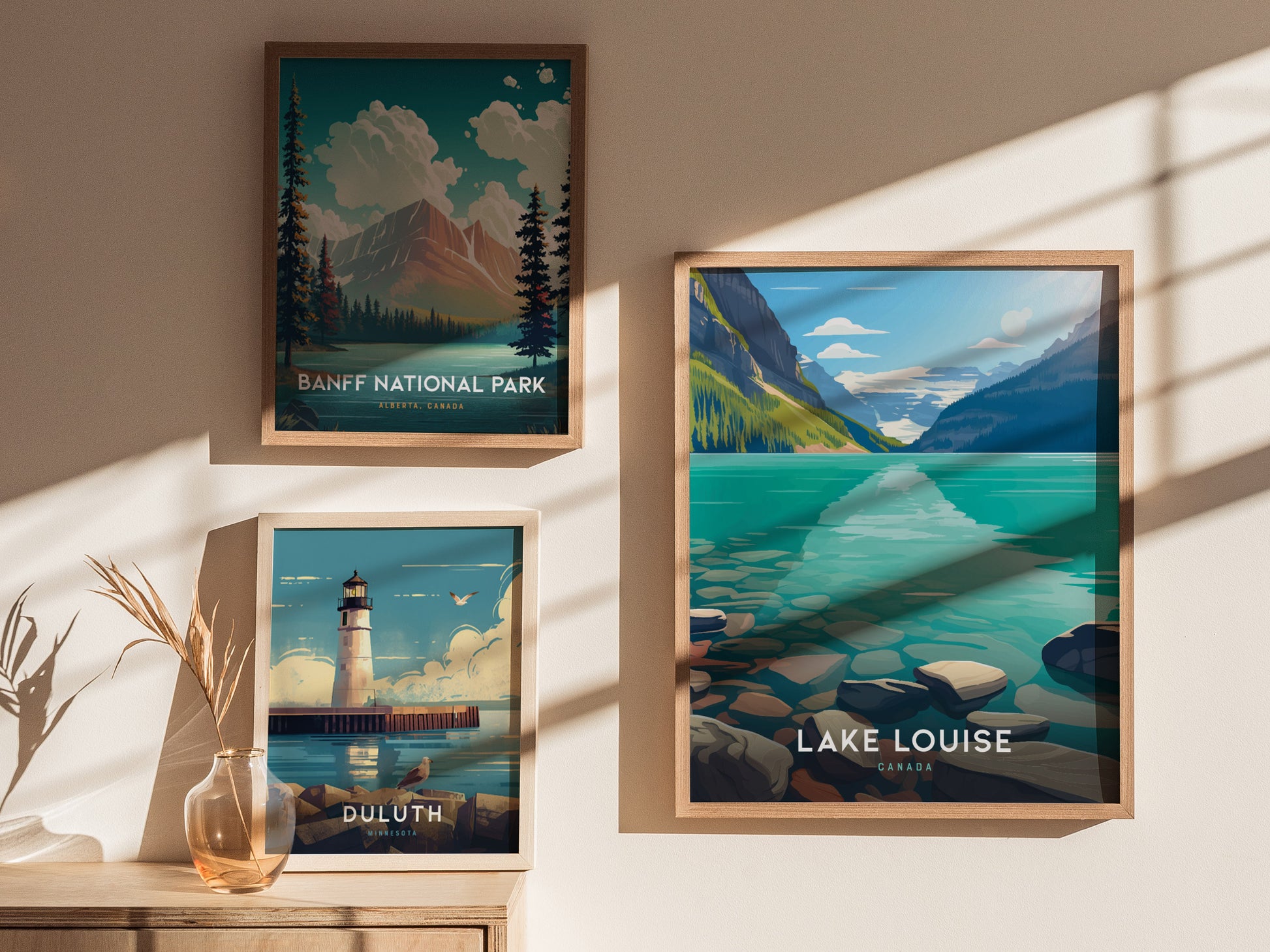 Three framed posters are displayed on a wall, depicting Banff National Park, Lake Louise with turquoise waters, and a lighthouse scene from Duluth, Minnesota, with soft sunlight and shadows.