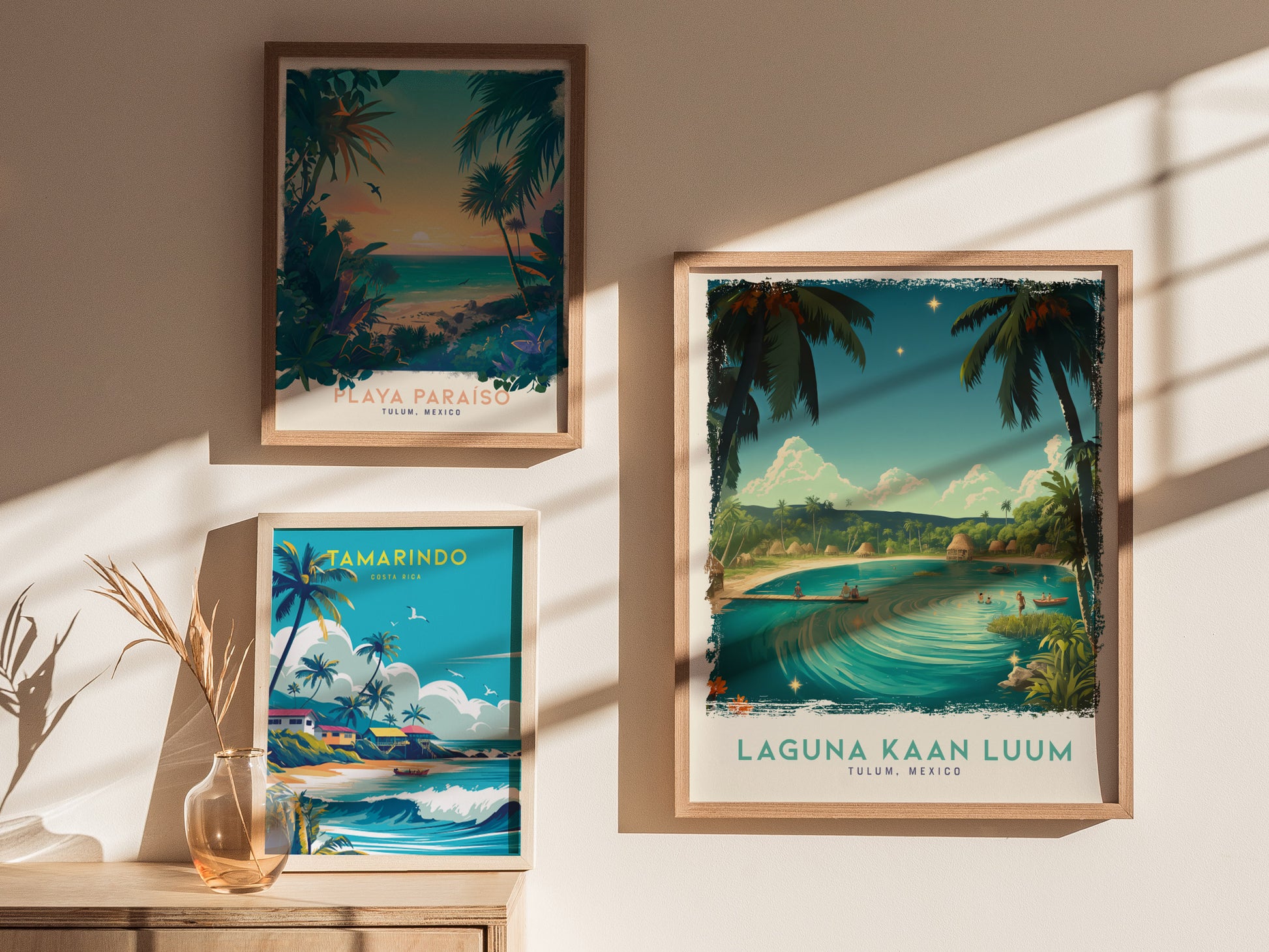 Three framed posters depicting tropical landscapes hang on a sunlit wall. The Laguna Kaan Luum poster shows a lagoon with palm trees and a serene atmosphere.
