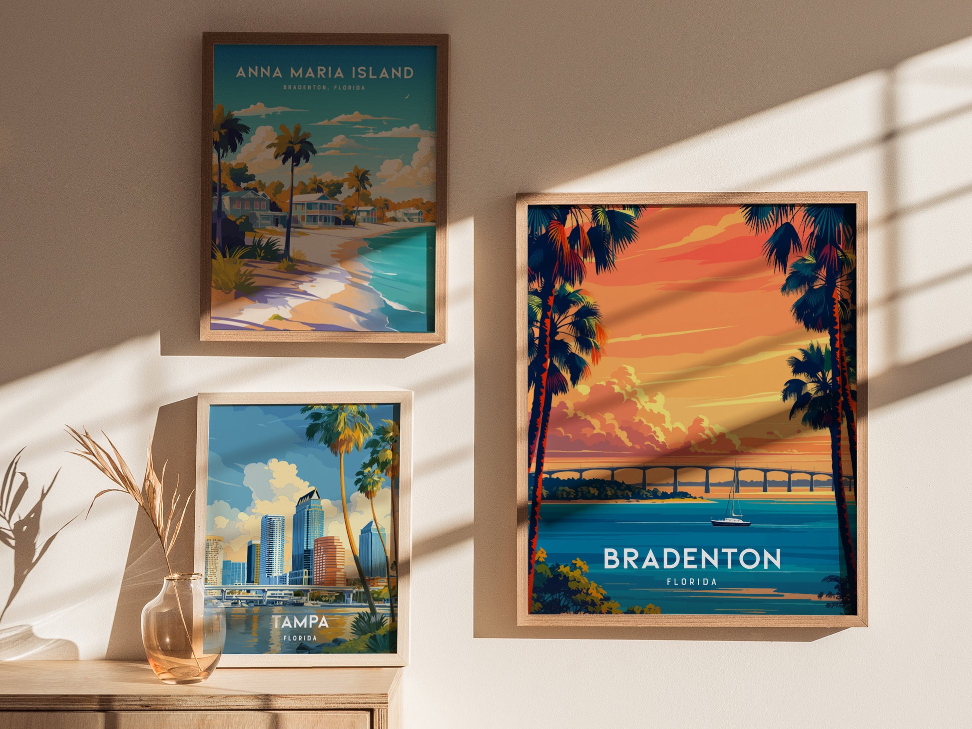 Framed posters of Anna Maria Island, Bradenton, and Tampa on a wall with sunlight casting shadows.
