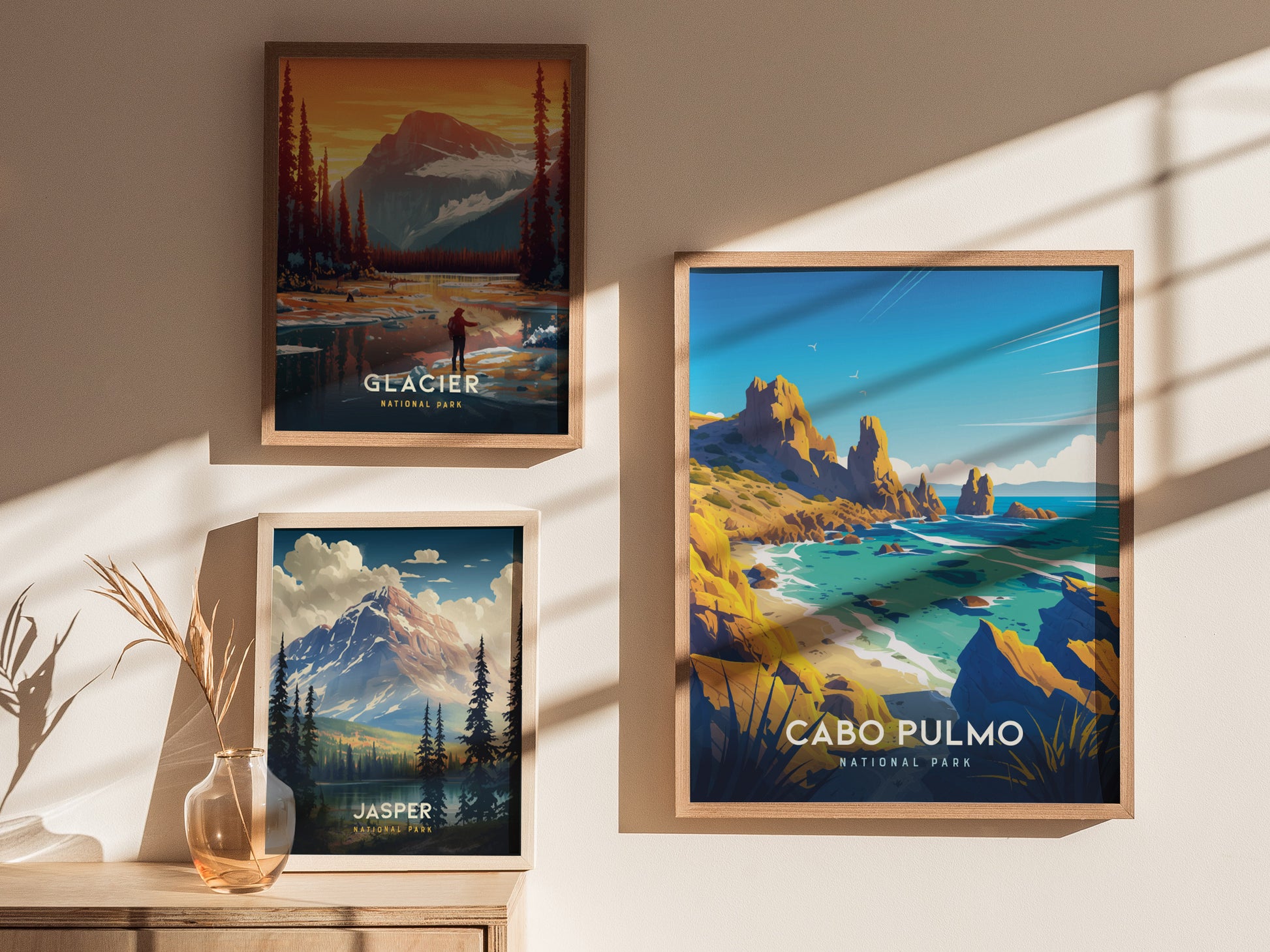 Three framed posters on a wall depict scenic landscapes: Glacier National Park, Jasper National Park, and Cabo Pulmo National Park, with warm sunlight casting shadows.