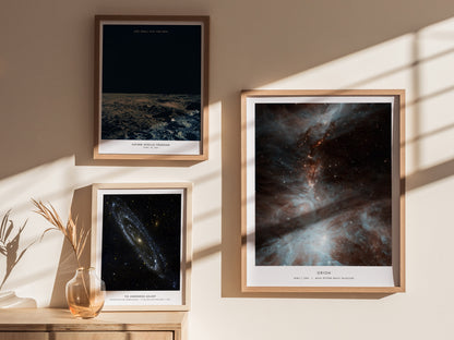 Three framed space-themed prints on a wall with sunlight casting shadows.