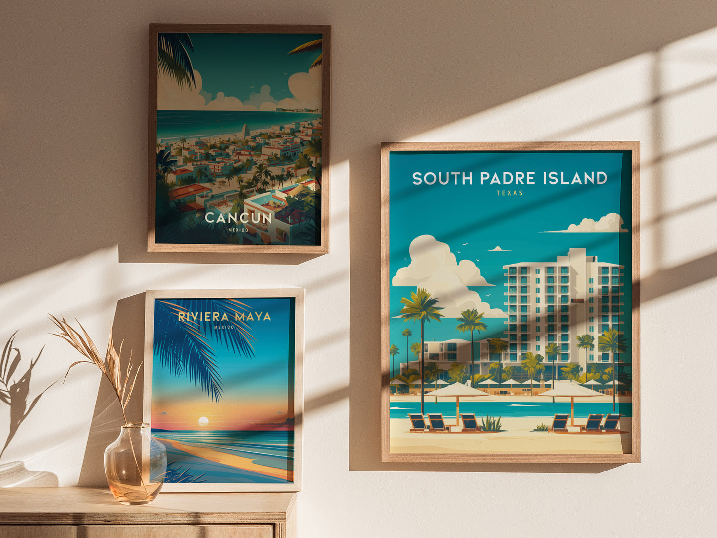 Three framed travel posters are displayed on a sunlit wall, showcasing illustrations of Cancun, Riviera Maya, and South Padre Island, each with vibrant coastal scenery and bold typography.