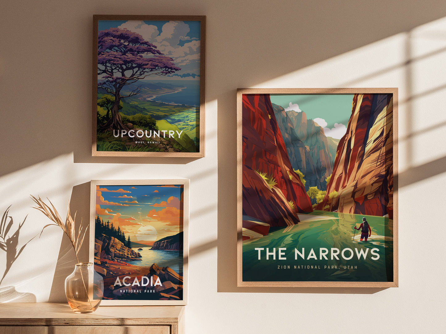 Three framed posters are displayed on a wall in sunlight: Upcountry with a scenic view, The Narrows featuring a canyon scene, and Acadia showing a coastal landscape.