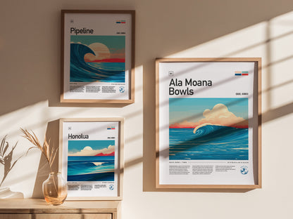 Framed surf-themed posters hang on a beige wall, featuring vibrant wave illustrations labeled Pipeline, Ala Moana Bowls, and Honolua. A decorative vase with dried grass sits on a wooden surface.
