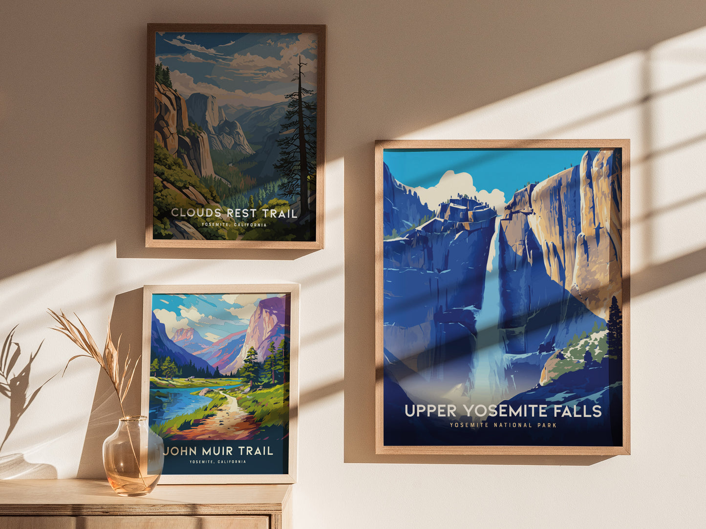 Three framed posters hang on a wall, depicting scenic trails in Yosemite National Park. Sunlight casts shadows across the images, highlighting vibrant landscapes and iconic natural features.