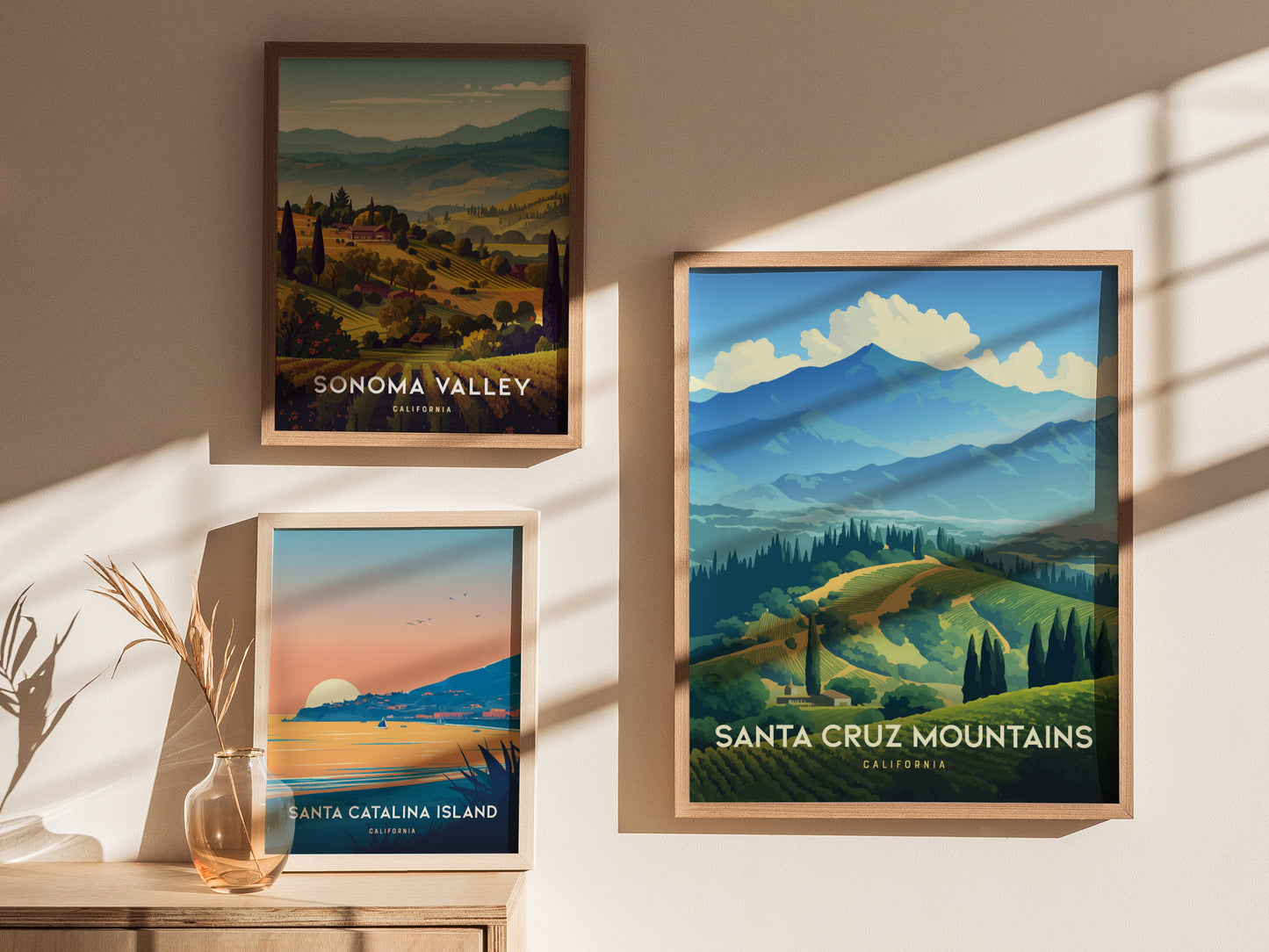 Three framed posters on a sunlit wall depict Sonoma Valley, Santa Cruz Mountains, and Santa Catalina Island landscapes, each showcasing vibrant natural scenery and lush greenery.
