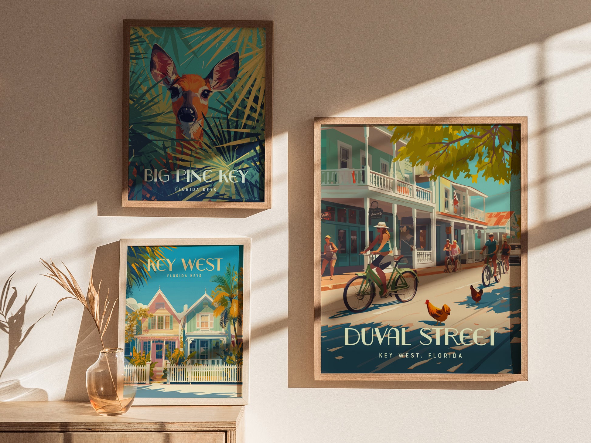 Three framed posters are displayed on a wall, depicting tropical scenes from the Florida Keys, including cyclists on Duval Street and vibrant imagery of Key West and Big Pine Key.